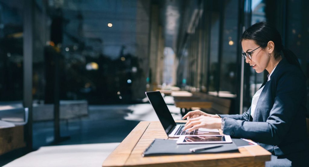 Side view of businesswoman in formal wear typing on laptop keyboard while sitting at table