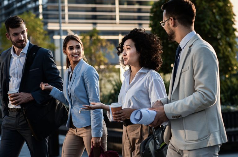 Group of business people walking outside in front of office buildings.