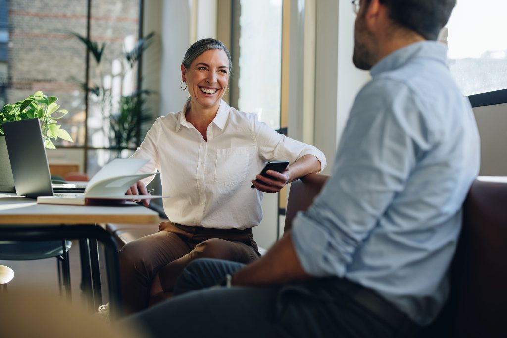 Woman talking with coworker at office desk. Businesswoman having discussion with team member in office.
