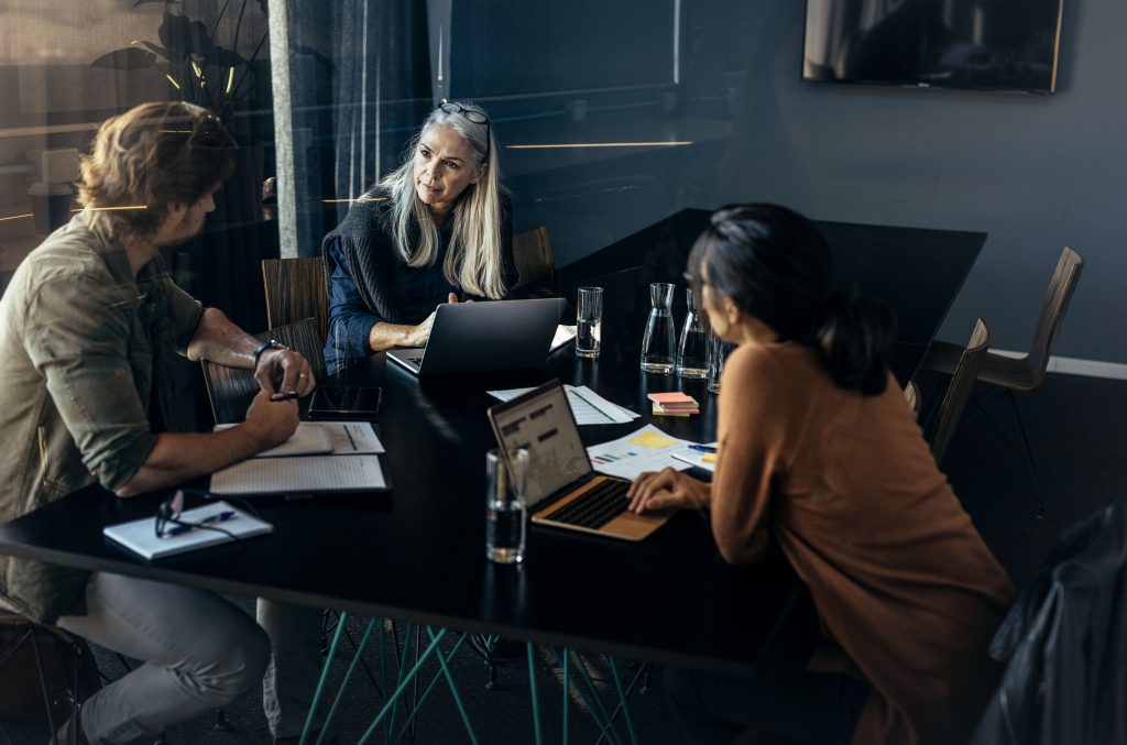 Three professionals sitting around a table and discussing work. Business team brainstorming new business ideas during meeting at office.