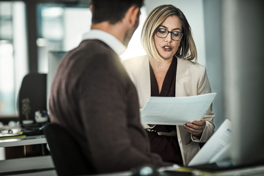 Shot of two businesspeople discussing a document while sitting at a desk